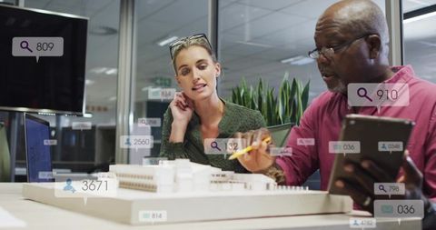 Architects collaborating over scale model using augmented reality tablet in modern office