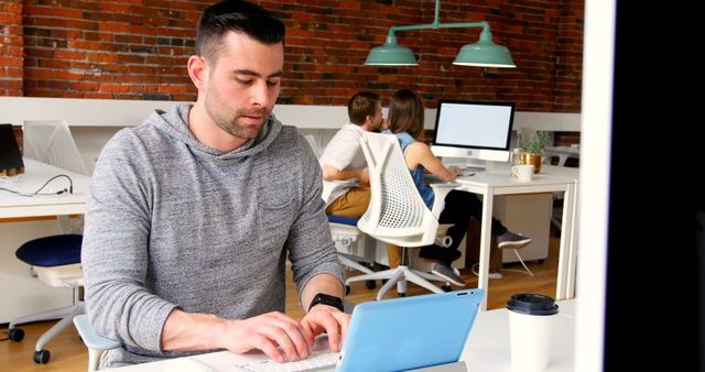 Focused Man Working in Modern Office Space with Brick Wall - Download Free Stock Images Pikwizard.com