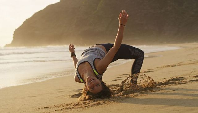 Sunset beach backbend: energetic woman doing yoga bridge on sandy oceanfront