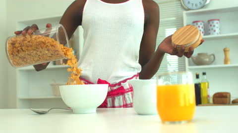 Woman Pouring Cereal into Bowl at Breakfast Routine