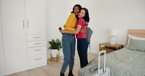 Mother and Daughter Hugging Joyfully with Suitcase in Bedroom