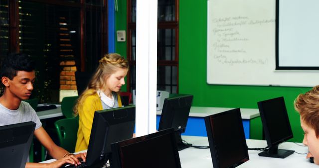 Students engaged in learning by working on computers in a classroom. Suitable for depicting modern education, technology use in schools, collaborative learning, or student group projects. Useful for educational materials, technology in education campaigns, school brochures, or promoting digital literacy.