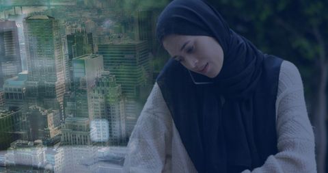 Middle eastern woman using smartphone with cityscape overlay