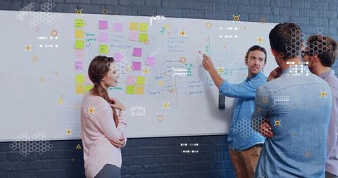 Creative Team Discussing Strategy with Flowchart on Whiteboard in Office