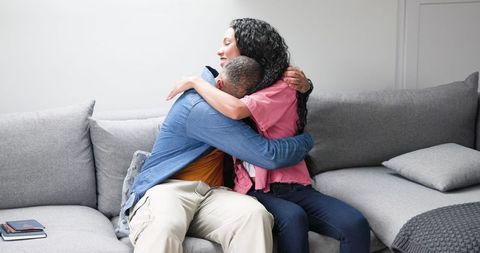 Happy Couple Embracing on Sofa During Travel Preparation