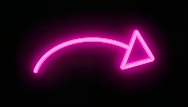 Glowing pink neon arrow sign on dark background