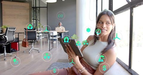Young woman using tablet in modern coworking space with floating sustainability icons