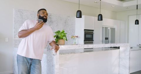 Casual African American Man in Modern Kitchen Relaxing with Smartphone