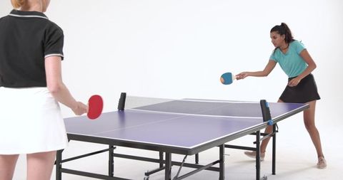 Women competing in intense table tennis match