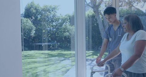 Home care nurse helping elderly woman with walker by patio doors in sunny backyard