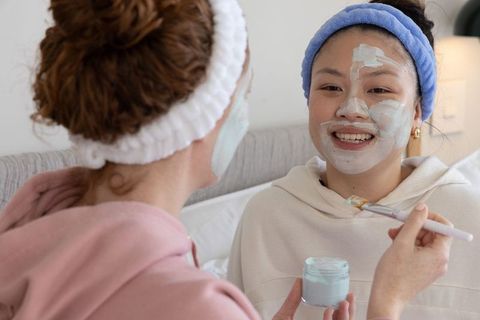 Friends applying face masks during cozy at-home spa night skincare ritual