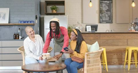 African american barista serving coffee to friends in cozy modern cafe interior