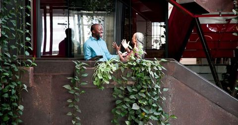 Couple Enjoying Moments on Balcony with Lush Green Surroundings