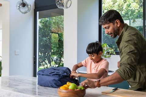 Indian Father and Son Unpacking Backpack in Modern Kitchen