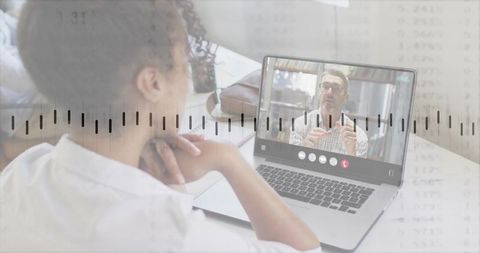Mid-adult woman watching virtual consultation on laptop with waveform overlay, homeoffice