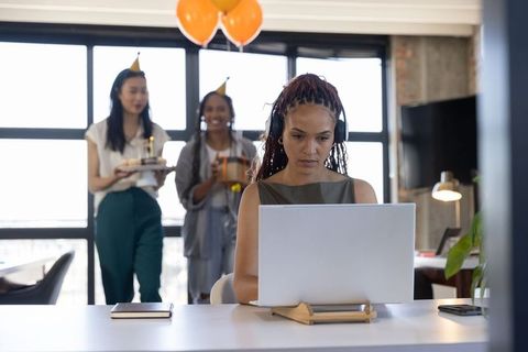 Diverse colleagues surprising birthday co-worker in office