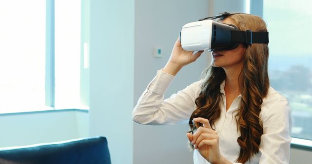 Young woman using virtual reality headset in modern office environment. Ideal for technology blogs, social media posts, educational resources, innovation in the workplace articles, and VR product promotions.