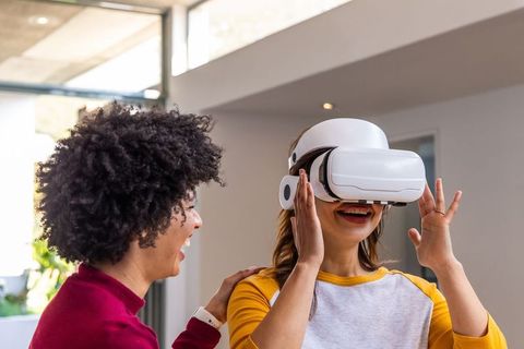Friends trying white vr headset in sunlit modern living room, laughing and connecting