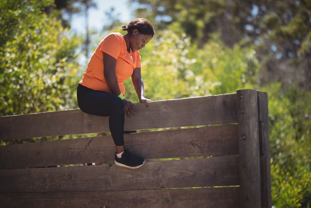 Determined woman climbing wooden wall during obstacle course in boot camp