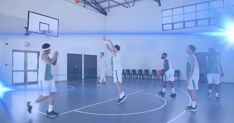 Basketball players practicing jump shot drill in indoor gymnasium with dramatic lens flare