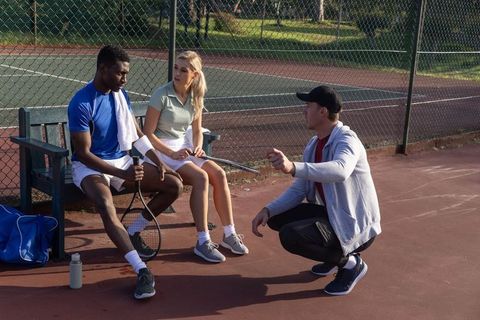 Tennis coach guiding players during court break, planning strategy and technique