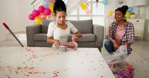 Women Enjoying Cleanup After Colorful Indoor Celebration