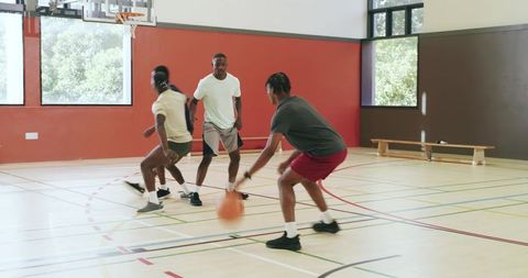 African american players executing crossover dribble during indoor basketball training session