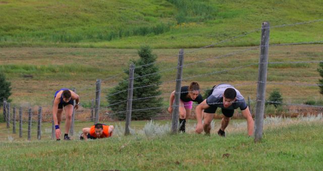 Individuals are engaged in an outdoor obstacle race, demonstrating teamwork and perseverance as they navigate a steep, grassy hill. This is ideal for content related to fitness challenges, adventure races, team building activities, and physical endurance.