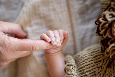 Newborn hand holding parent finger
