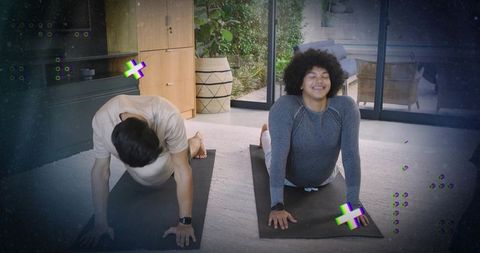 Two men practicing cobra backbend yoga on mats in bright living room with patio view