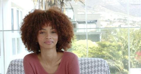 Smiling african american woman relaxing in bright sunroom with contemporary decor