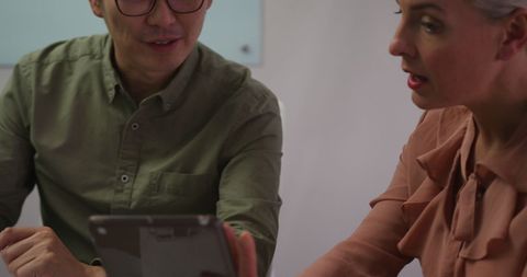 Colleagues Collaborating with Tablet in Office Meeting