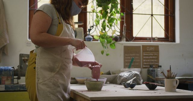 Masked Artisan Pouring Liquid Clay in Creative Workshop - Download Free Stock Images Pikwizard.com