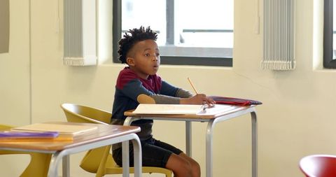 African American Boy Learning and Writing at Classroom Desk