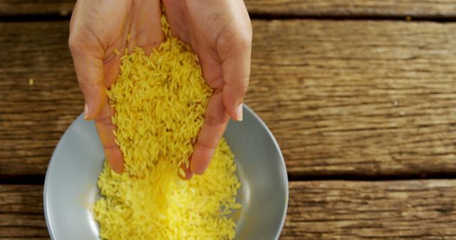 Hands Pouring Yellow Rice into Bowl on Rustic Wooden Table - Download Free Stock Images Pikwizard.com