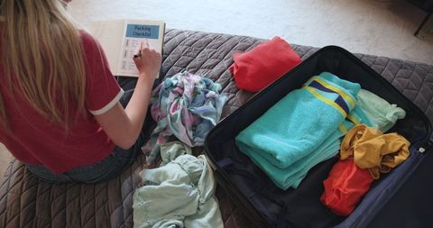 Teen girl planning trip with packing checklist and suitcase