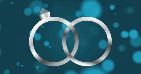 Interlocking silver wedding ring and diamond engagement ring on teal bokeh background