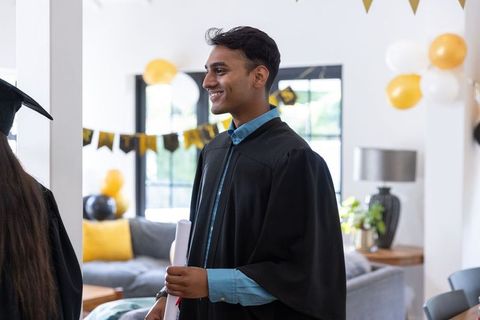 Asian Friends Celebrating Graduation at Home with Gowns and Decorations