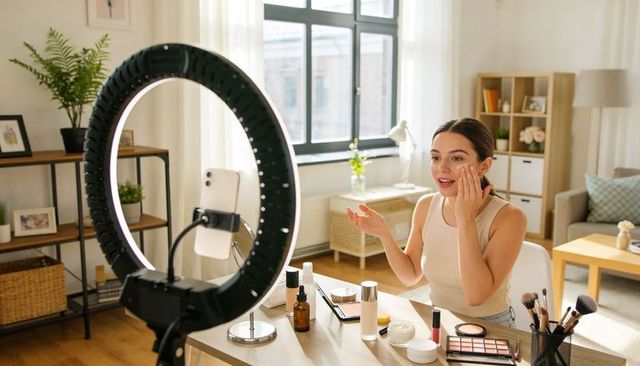 Beauty creator applying skincare on camera using led ring light for makeup tutorial live