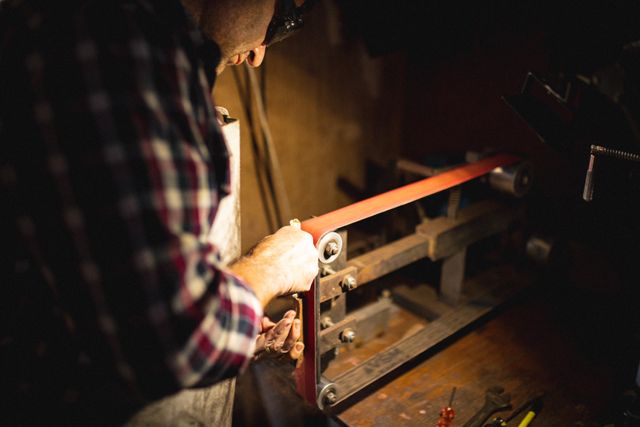 Caucasian male knife maker wearing apron using sander in workshop - Download Free Stock Photos Pikwizard.com