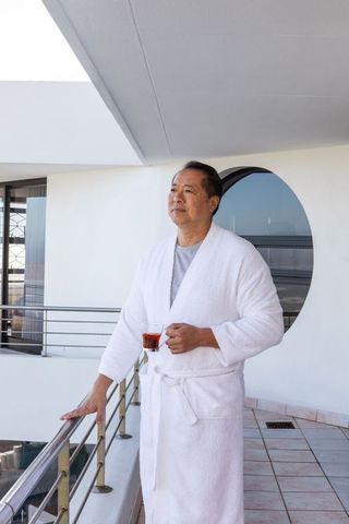 Mature Asian Man Enjoying Tea on Modern Balcony