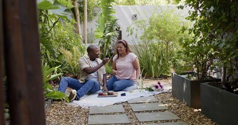 Diverse Couple Enjoying Picnic Amidst Greenery in Serene Garden