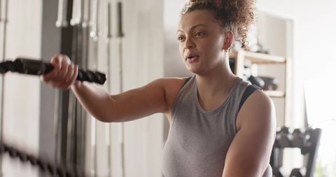 Woman training with battle ropes in gym for intense strength and cardio conditioning