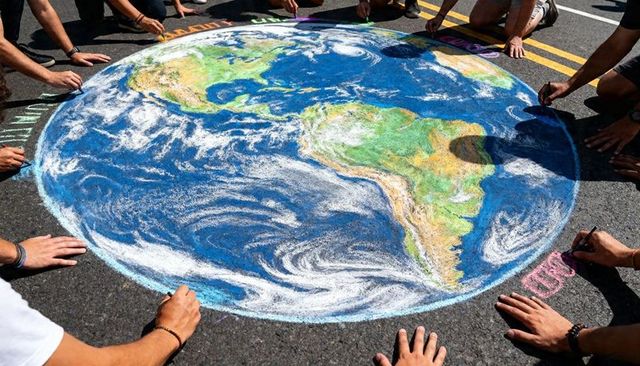 Community creating giant chalk earth on street for climate action and public art