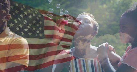Family blowing bubbles outdoors with american flag overlay celebrates unity