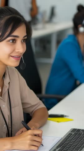 Female customer service agent answering call and taking notes at office vertical video