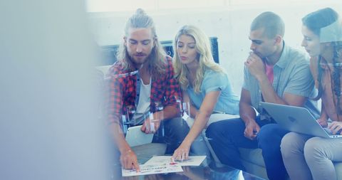 Young Professionals Engaged in Collaborative Discussion with Modern Technology