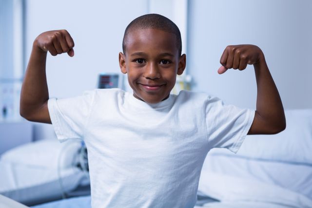 Portrait of boy flexing his muscles in ward at hospital