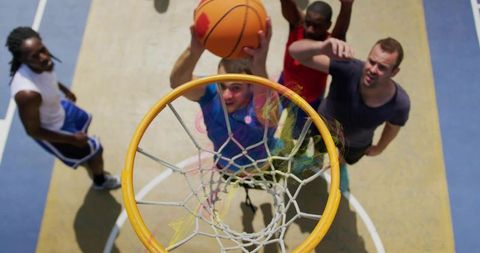 Jumping player reaching for dunk at outdoor basketball hoop on sunny urban court