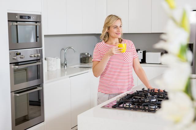 Thoughtful woman holding coffee mug in kitchen at home